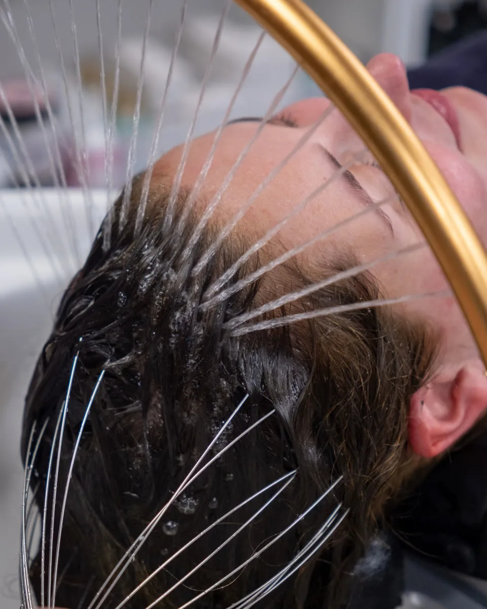 Een klant ontspant onder de waterboog tijdens een Japanese Head Spa.