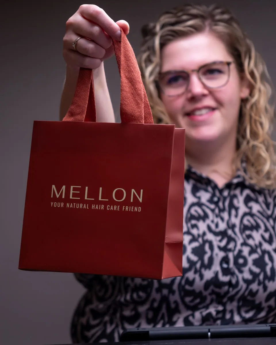 Francis overhandigt een rode Mellon-producttas in de salon.
